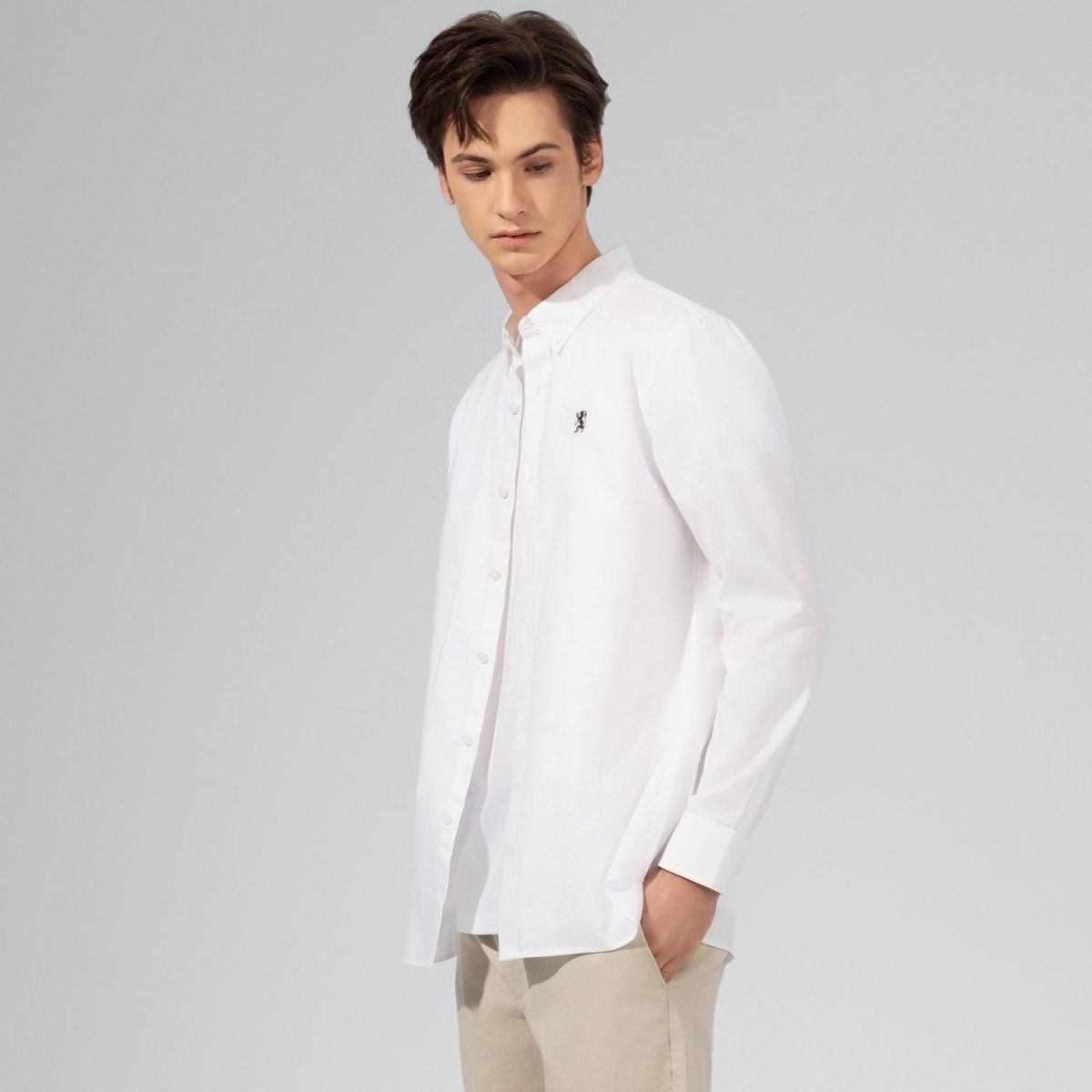 Giordano white oxford shirt with lion embroidery worn by male model with beige pants